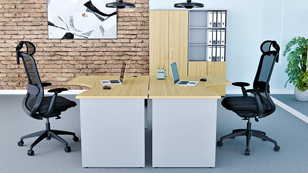 Dwa niebieskie, tapicerowane krzesła obrotowe zostały ustawione przy stanowisku pracy obejmującym biurko i monitory ekranowe.